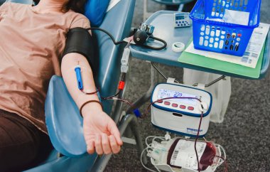 Kanepeye uzanmış bir kadın, kan bağışı sırasında kolunda iğne ve kan toplama cihazı olan bir kadın. Hastanede kan nakli. Gönüllü fedakarlık için Phlebotomy. Kan Bağışı Merkezi