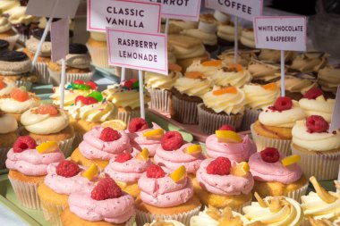 Menüler, kafe promosyonları, yemek başlıkları, tarifler ve yaşam tarzı konsepti için pastane sunumunda taze lezzetli tatlar ve dokuların etiketleriyle standlarda çeşitli cazip muffinler sergileniyor.