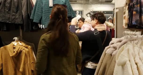 Женщина с ребенком выбирает одежду во время покупок — стоковое видео