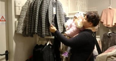 Alışveriş sırasında bebek giysileri seçerek kadınla