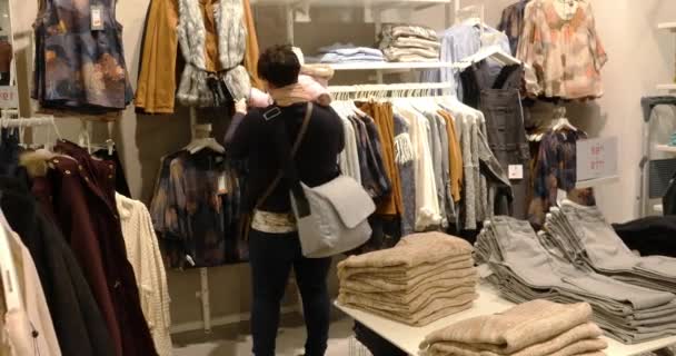 Mujer con bebé eligiendo ropa durante las compras — Vídeo de stock