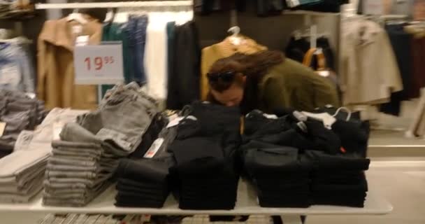 Жінка вибирає одяг під час покупок — стокове відео