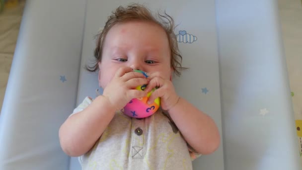 Schattige baby liegen en houden een bal — Stockvideo