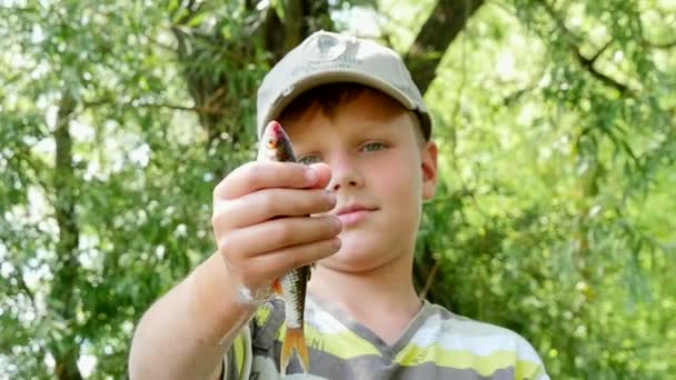 Niño sosteniendo un pez en su mano cámara lenta — Vídeos de Stock