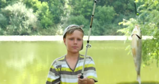 Молодой кавказский мальчик с удочкой и рыбой — стоковое видео