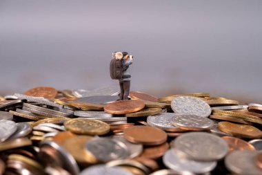 Bir fotoğrafçının küçük bir heykeli büyük bir madeni para yığınının üzerinde duruyor, bir kameraya nişan alıyor, macera ve finansmanı birleştiren eşsiz bir sahne yaratıyor..