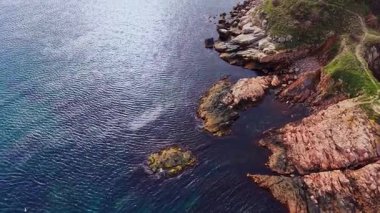 Bulgaristan 'ın engebeli kıyı şeridine ait hava manzarası kayalık oluşumlar ve berrak suları gösteriyor. Sahne, sahilin güzelliğini ve doğal özelliklerini vurguluyor..