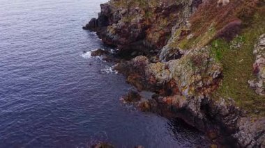 Bulgaristan 'ın kayalık kıyı şeridini gösteren hava manzarası, kayalıkların canlı renklerini ve derin mavi suları vurguluyor. Doğanın güzelliği bu sahnede yakalanır..