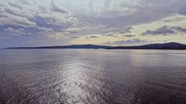 Barışçıl bir manzara, Bulgaristan 'ın kıyı şeridinde bulutları yansıtan sakin suları gösteriyor. Manzara, gün batımında dramatik bir gökyüzünün altındaki uzak tepeleri kapsar..