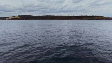 Sersemletici hava perspektifi, Bulgaristan 'ın sakin kıyı şeridini hafif dalgalar ve bulutlu gökyüzünün altındaki uzak tepelerle göstererek keşif ve rahatlamaya davet ediyor.