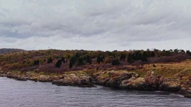 Bulgaristan 'ın kıyı şeridinde güneş batarken kayalık kıyılar ve renkli bitkiler sergileniyor. Bu manzaralı hava manzarası bölgenin doğal güzelliğini ve sükunetini yansıtıyor..