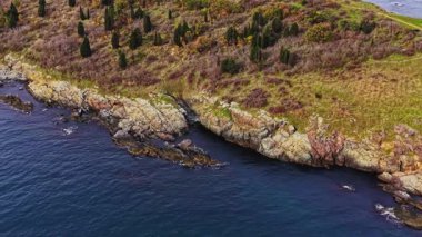 Bulgaristan 'da engebeli bir kıyı şeridi ve yeşil tepeler havadan çekiliyor. Berrak mavi su, kayalık kıyılar ve sık ağaçlarla çok güzel tezat oluşturuyor..