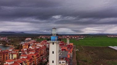 Hava perspektifi, Bulgaristan 'da karamsar bir gökyüzü altında canlı evler ve tarlalarla çevrili bir deniz fenerini yakalıyor. Sahne, bölgenin güzelliğini gözler önüne seriyor.
