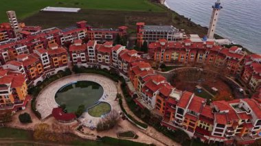 Bu kuş bakışı Bulgaristan 'da yemyeşil tarlalar ve denizle çevrili renkli bir sahil beldesini gösteriyor. Mimaride canlı binalar ve havuz alanı yer alıyor..