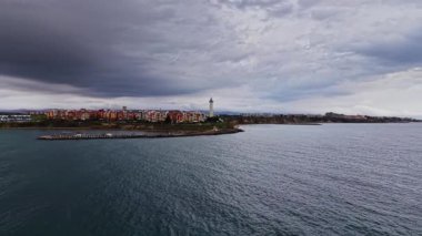 Bu insansız hava aracı görüntüsü Bulgaristan 'ın kıyı şeridini yakalıyor, bulutlu bir gökyüzünün altında deniz feneri ve deniz kenarındaki konutları vurguluyor..