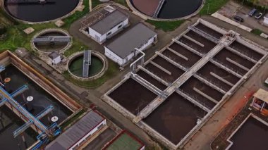 Görüntü, birden fazla tank ve tesisi olan bir atık su arıtma tesisinin havadan görüntüsünü gösteriyor. Çeşitli süreçler su arıtma çabalarını gösteriyor.
