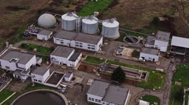 Atık su arıtma tesisinin hava görüntüsü bulutlu bir günde birkaç büyük depolama tankı, tedavi ekipmanı ve çevreleyen yeşillikleri gösteriyor..