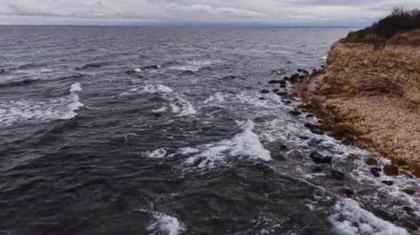 Bu hava çekimi, Bulgaristan 'ın engebeli kıyı şeridini, kayalık kıyıları ve bulutlu bir gökyüzü altında dalgalanan okyanus dalgalarını gözler önüne seriyor..