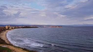 Soluk kesici drone çekimi, sakin Bulgar kıyı şeridini yumuşak dalgalar, kumlu plaj ve renkli bir akşam gökyüzü altında pitoresk bir gökyüzü altında yakalıyor.