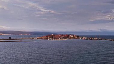 Bulgaristan 'ın Nesebar kentinin hava manzarasında limana kenetlenen tarihi binalar, kıyı şeridi ve tekneler görülüyor. Sahne, bölgenin huzurlu güzelliğini yansıtıyor..