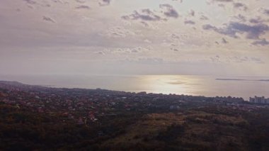 Büyüleyici bir hava manzarası, gün batımını yansıtan parıldayan denizin yer aldığı Bulgaristan 'ın kıyı manzarasını gözler önüne seriyor. Yakınlardaki tepeler ve kentsel alanlar manzaraya derinlik katar.