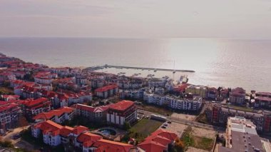 Bu hava manzarası, Bulgaristan 'ın güzel sahil kenti Burgaz' ı, renkli çatılar ve altın saat aydınlığını yansıtan sakin bir limanı yansıtıyor..