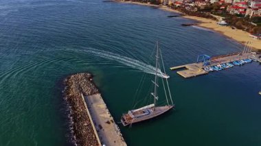 Canlı hava manzarası Bulgaristan 'da bir marinayı çekiyor. Dalgalar kıyıya vururken yelkenliler rıhtımda kuyruk oluyor. Manzaralı kıyı manzarası hareketli bir atmosfer sergiliyor.