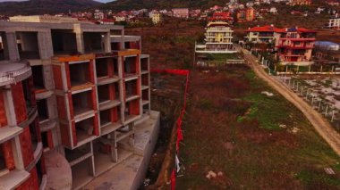 Bitmemiş yapılar, Bulgaristan 'ın kıyı bölgesindeki gelişmiş evlerin yanında duruyor ve bu da inşaat ile yeşil tepeler arasında tamamlanmış konutlar arasında bir tezat oluşturuyor..