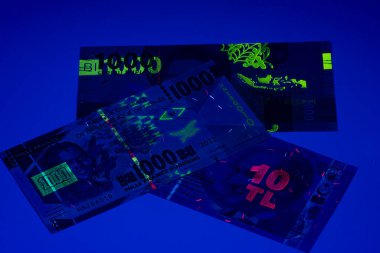 Birçok banknot ultraviyole ışık altında sergilenir. Para birimindeki detaylar ve güvenlik özellikleri karanlık ortamda görülebilir..