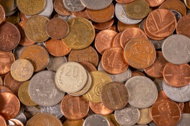 Düz bir yüzeye yayılmış bozuk paraların bir karışımı farklı boyut ve tipleri gösterir. Bazı paralar eski, diğerleri daha yeni görünüyor..