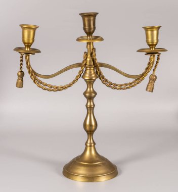 Bu şamdanın üç tane mum tutacağı var ve kollarında çarpık bir dizayn var. Pirinçten yapılmış ve yuvarlak bir zeminde duruyor..