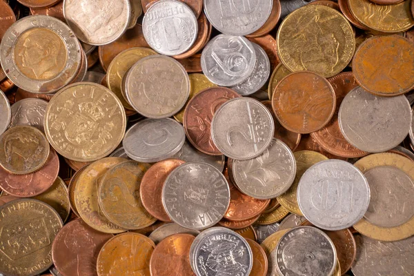 Düz bir yüzeye çeşitli madeni paralar saçılmıştır. Bozuk paralar farklı boyut ve renkleri gösterir, gündüz boyunca ışığı farklı şekillerde yansıtır..