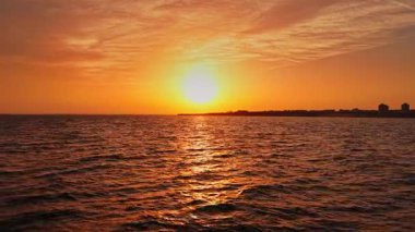 Sıcak bir günbatımı, Bulgaristan 'ın Nesebar kenti yakınlarında güneş batarken suyun üzerinde turuncu renkler bırakıyor. Sakin dalgalar akşam ışığını yansıtıyor, sakin bir sahil manzarası yaratıyor..