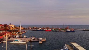 Nesebar 'daki limanda sakin bir günbatımında sakin denize karşı renkli balıkçı tekneleri ve yatlar sergileniyor. Bölge büyüleyici binalarla dolu..