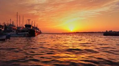 Bulgaristan 'ın Nesebar kentindeki limanın muhteşem günbatımı manzarasının tadını çıkar. Sıcak renkler, tekneler huzur içinde dinlenirken suyu yansıtıyor ve sakin bir atmosfer yaratıyor..