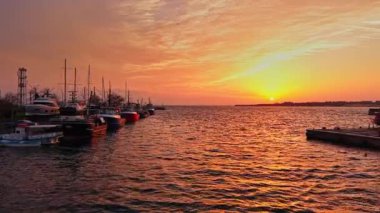Güneş Bulgaristan 'ın Nesebar kentinin sakin limanında batıyor, suya canlı renkler döküyor ve rıhtım boyunca bağlı balıkçı teknelerini aydınlatıyor..