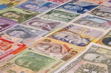 Birçok ülkeden gelen çeşitli banknotlar düzgünce bir masanın üzerinde düzenlenir. Notlar, kendi para birimlerini temsil eden farklı tasarım ve renkleri gösteriyor..