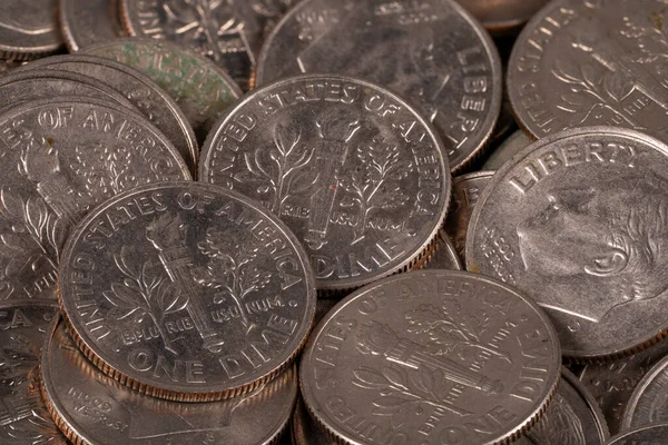 Birçok gümüş sikke bir araya toplanmış, Amerikan paralarının yüzlerini ve tasarımlarını gösteriyor. Işığı yansıtırlar ve zamanla hafif bir yıpranma gösterirler..