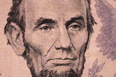 Bir banknota yakından bakıldığında tarihi bir şahsın yüzü görülüyor. Tasarım, kişinin yüz yapısı ve ifadesinin detaylarını içerir..