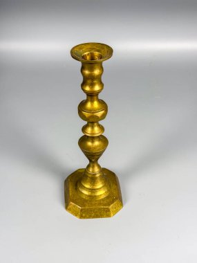 Altın bir şamdan pürüzsüz bir yüzeyde dikilir. Tasarımı, detay ekleyen bir dizi şekle sahiptir. Işık yansıyor, parlak yüzeyini gösteriyor..
