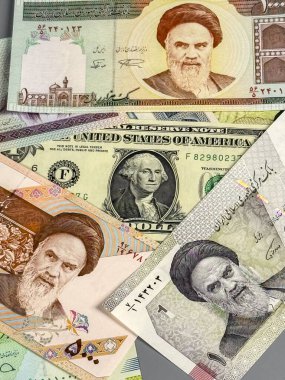 Düz bir zeminde farklı banknotlar düzenlenir. Notlarda çeşitli şekiller ve semboller gösteriliyor. Para birimleri arasında ABD doları ve İran ritüelleri yer alıyor..