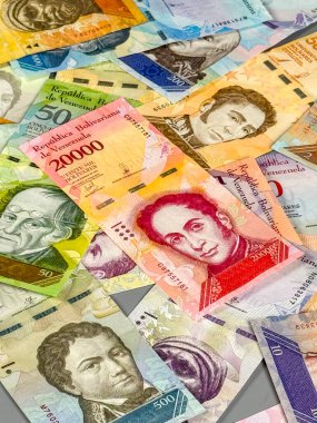 Venezuela 'dan farklı değerlere sahip birçok banknot gri bir yüzeye yayılmıştır. Notlarda tarihsel figürler ve renkli tasarımların portreleri yer alıyor..