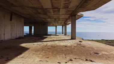 Havadan bakıldığında sakin okyanusa bakan boş bir beton yapı görülüyor. Yerdeki gölgeler sakin ve ıssız bir atmosferi işaret ediyor..