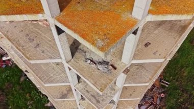 Hava manzarası uzun ve terk edilmiş bir yapıyı yakalar, aşınmış yüzeylerini ve aşırı gelişmiş çevresini gösterir, kentsel bozulma ve ihmal belirtileri gösterir..