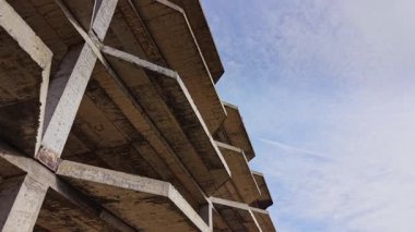 Bu hava çekimi, mavi gökyüzünün altında bitmemiş beton bir yapı yakalıyor. Perspektif, inşaat projesinin hammadde ve tasarımını vurgular.