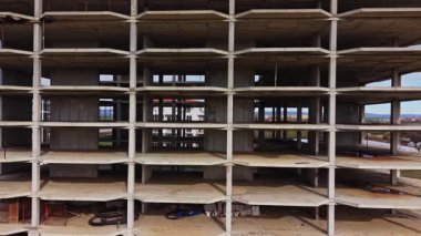 Hava görüntüsü çok katlı bir binanın yapım aşamasında olduğunu gösteriyor. Yapının beton iskeleti, gelecekteki zemin ve pencereler için boş alanlar ile görülebilir.