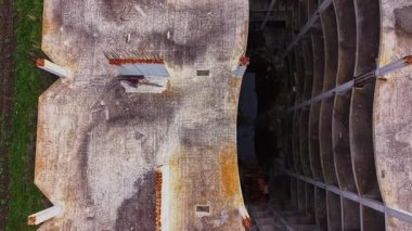 Bu hava görüntüsü paslanmış elementleri ve yerde büyük bir deliği olan çökmekte olan bir yapıyı yakalar. Çevredeki yeşillik, binanın çürümesiyle çelişiyor..