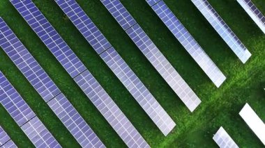 Hava görüntüsü yemyeşil arazide sıralanmış güneş panelleri gösteriyor, yenilenebilir enerji girişimlerini ve faaliyette sürdürülebilir uygulamaları vurguluyor.