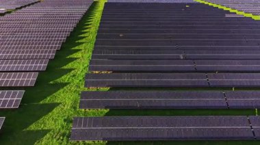 Güneş panellerinin sıraları yeşil alanlar boyunca uzanıyor ve temiz bir enerji manzarası yaratıyor. Parlak güneş bu yenilenebilir enerji kaynağının verimliliğini arttırır..