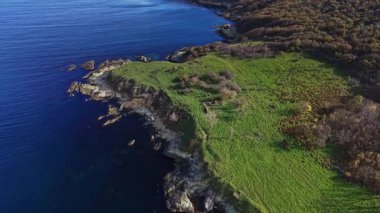 Hava perspektifi, derin mavi sulara düşen yemyeşil uçurumları yakalar. Sakin kıyı şeridi kayalık oluşumlarla ve berrak, sakin denizlerle sınırlıdır..
